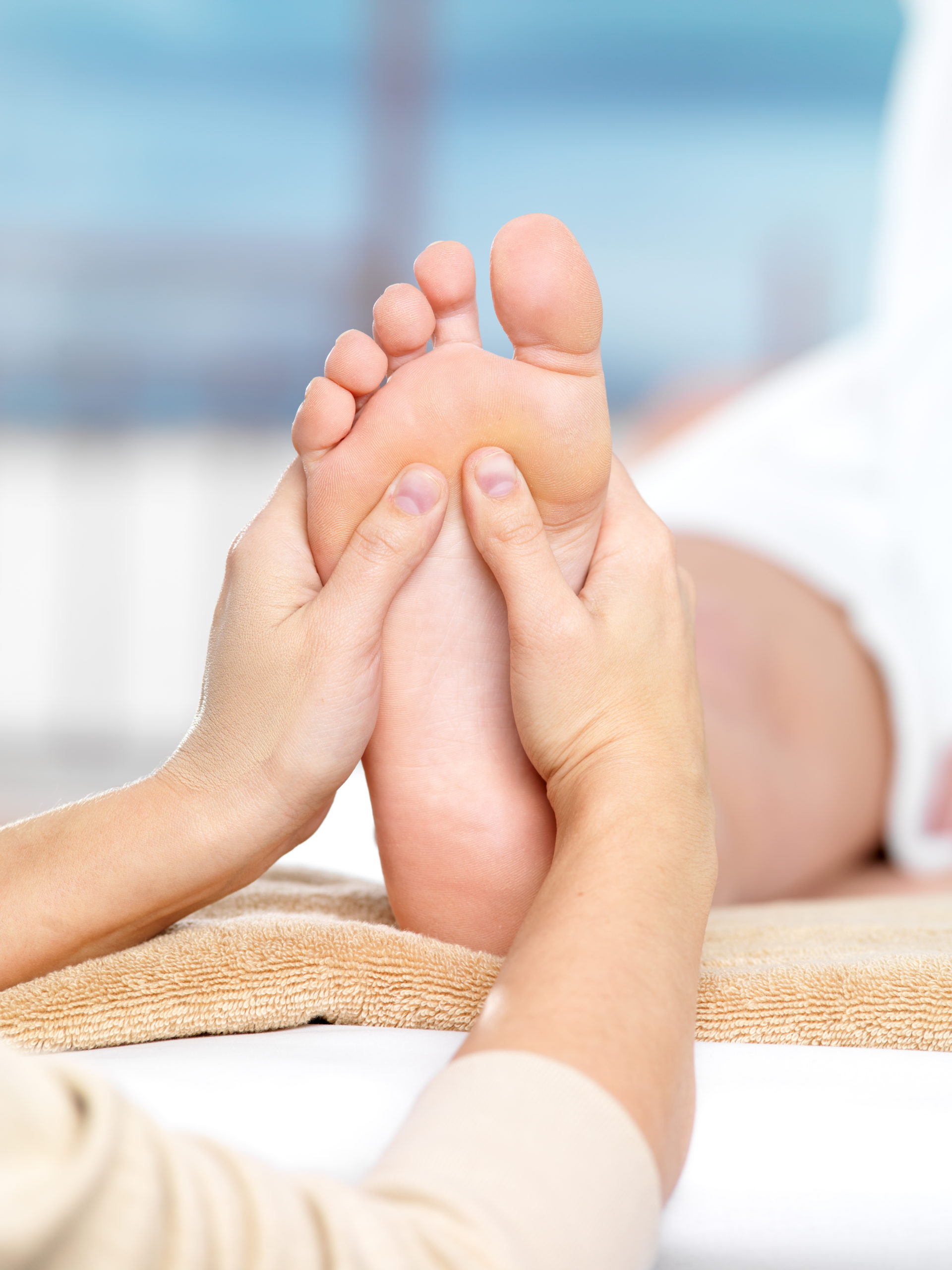 Massage on the foot in spa salon, close-up shot - colored background